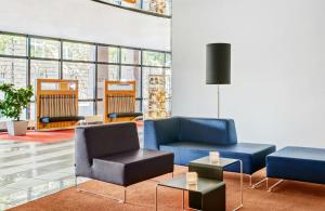 a lobby with couches and chairs and a table at Hotel Erfurt City Center by Leonardo Hotels in Erfurt