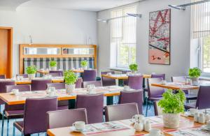 a dining room with tables and purple chairs at Hotel Erfurt City Center by Leonardo Hotels in Erfurt