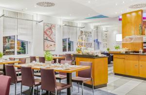 a restaurant with tables and chairs and a kitchen at Hotel Erfurt City Center by Leonardo Hotels in Erfurt