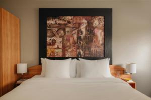 a bedroom with a white bed with a painting on the wall at Leonardo Hotel Groningen City Center in Groningen