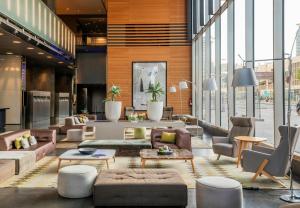 a living room with couches and tables and windows at Leonardo Royal Hotel Barcelona Forum in Barcelona