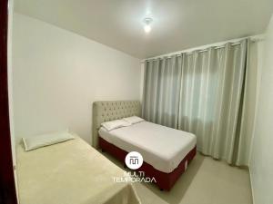 two beds in a small room with a window at Casa Aconchego Barra Velha/SC in Barra Velha
