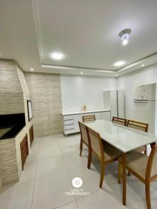 a dining room with a white table and chairs at Casa Aconchego Barra Velha/SC in Barra Velha +4 photos