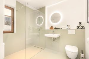 a white bathroom with a sink and a toilet at Alpen Lodge Samerberg in Samerberg