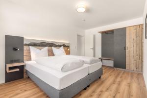 a bedroom with a large white bed with wooden floors at Alpen Lodge Samerberg in Samerberg