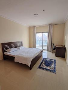a bedroom with a bed and a desk and a window at King bed sea view in Sharjah