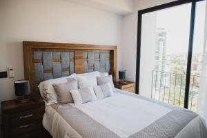 a bedroom with a white bed with a large window at Livet Ottawa 802 in Guadalajara