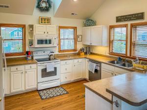 a kitchen with white appliances and wooden floors and windows at Raspberry Duck - Duck Landing, 525 Yds to Beach, Pool, Tiki Bar, Hot Tub, Close to Downtown in Duck