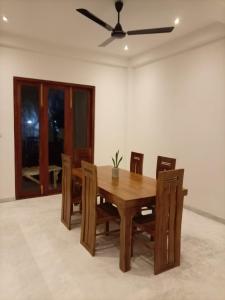 a wooden dining room table with chairs and a ceiling fan at Villa Nimāmi in Ahangama