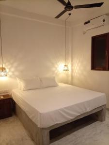 a bedroom with a white bed with two lights on it at Villa Nimāmi in Ahangama