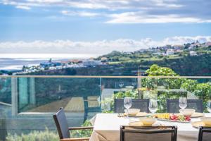 a table with wine glasses on a balcony with a view at Half Gate Villa - Ocean View & Private Pool in Gaula +37 photos