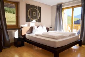 a bedroom with a bed with white sheets and a window at Landhaus Anita Dolomiten Kronplatz in Perca