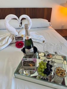 a tray with a bottle of champagne and grapes on a bed at Hotel Ipe in Barreirinhas