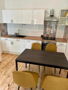 a kitchen with white cabinets and a table and chairs at Giulia Vendégház in Balatonboglár