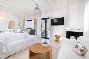 a living room with white furniture and a fireplace at Princess Villas Oasis Mykonos in Kalafatis +88 photos
