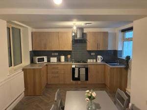 a kitchen with wooden cabinets and a table with flowers on it at Flat in Pont y Rhyl in Pont y Cymmer