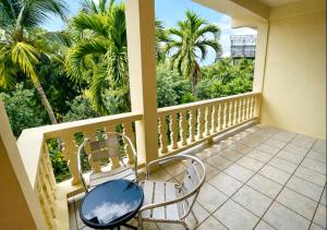 a balcony with two chairs and palm trees at Dennis' Hideaway in Mayreau