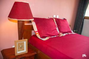 a red bed with a red pillow and a lamp at Chez Rossa à Deido in Douala