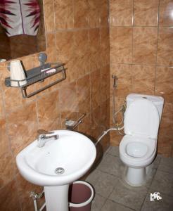 a bathroom with a white sink and a toilet at Chez Rossa à Deido in Douala
