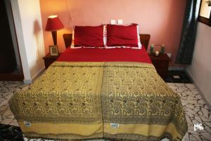 a bedroom with a bed with a red and yellow blanket at Chez Rossa à Deido in Douala