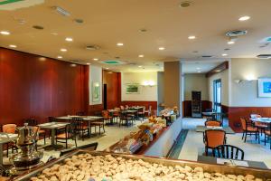 a restaurant with tables and chairs and a buffet at Hotel Excelsior Magenta in Magenta