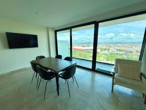 ein Esszimmer mit Tisch und Stühlen und großen Fenstern in der Unterkunft Central 102 Malecón in Mazatlán