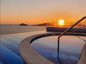 Ein Swimmingpool mit dem Sonnenuntergang im Hintergrund in der Unterkunft Central 102 Malecón in Mazatlán