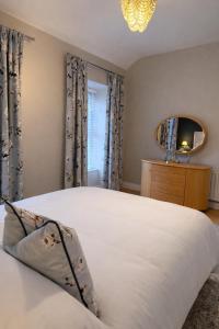 a bedroom with a large white bed and a mirror at Derry City Centre Townhouse in Derry Londonderry