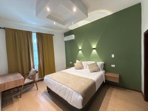 a bedroom with a bed and a green wall at Hotel B&B Nativo Peñón in Cali