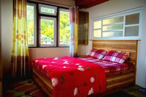 a bedroom with a bed with a red blanket at Bethany Homestay in Kalimpong