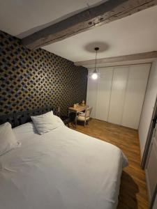 a bedroom with a white bed and a table at Maison village in Sérignan
