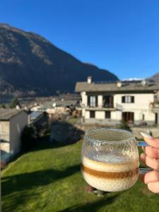 a person holding a glass of wine in front of a house at B&B Sentiero Rusca in Sondrio