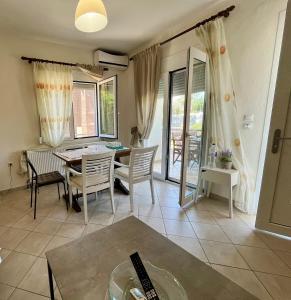 a living room with a table and chairs and windows at Soso studios & apartments in Stavros