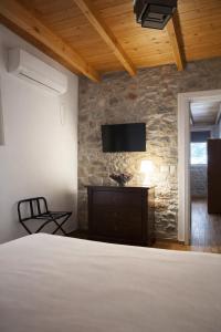 a bedroom with a bed and a tv on a stone wall at Lalloudes Hotel Mani in Éxo Nímfion