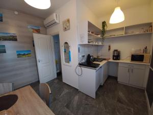 a small kitchen with white cabinets and a table at Bella Badacsony Apartmanház in Badacsonytomaj +24 photos
