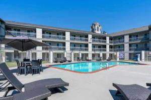 a hotel with a swimming pool with chairs and an umbrella at Antioch Inn and Suites in Antioch