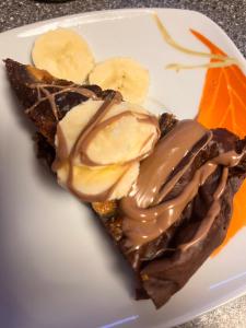 a piece of pie with chocolate and bananas on a plate at Žilina in Čadca