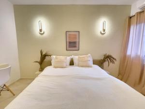 a bedroom with a large white bed with two pillows at Bohemian & White Getaway Zone4 in Abidjan