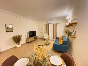 a living room with a blue couch and a table at Bohemian & White Getaway Zone4 in Abidjan