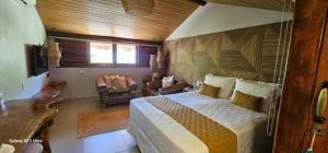 a bedroom with a bed and a living room at Wassu Pousada in São Miguel dos Milagres