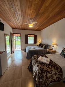 a bedroom with two beds and a wooden ceiling at Pousada Chalés Jatobá in Prados