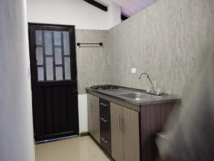 a small kitchen with a sink and a black door at Mi Cabaña in Nimaima