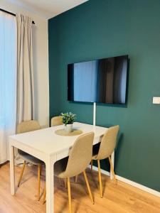 ein weißer Esstisch mit Stühlen und einem Fernseher in der Unterkunft White Inn - Statement in Mürzzuschlag + 1 Foto