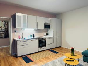 eine Küche mit weißen Schränken und einem Tisch in einem Zimmer in der Unterkunft White Inn - Statement in Mürzzuschlag