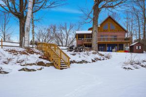 a log home in the snow with a wooden staircase at Schroon Lake Retreat in Schroon Lake