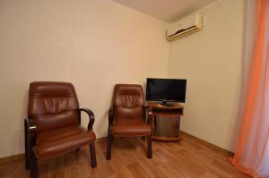 Zimmer mit 2 Stühlen, einem TV und einem Tisch in der Unterkunft Apartment on Navarynska in Mykolajiw