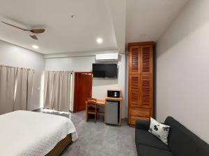 a bedroom with a bed and a desk and a couch at MeMe's Place in Placencia
