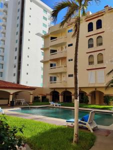 a hotel with a palm tree and a swimming pool at Comfortable apartment, right on the seafront in Mazatlán