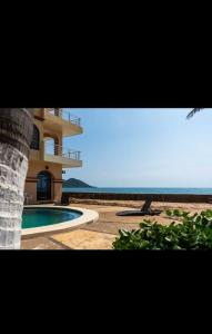 a building with a swimming pool next to the ocean at Comfortable apartment, right on the seafront in Mazatlán