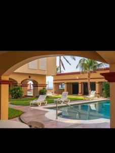 a house with a swimming pool and two lawn chairs at Comfortable apartment, right on the seafront in Mazatlán